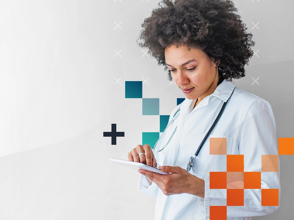 Female doctor in a white coat using a tablet, with a stethoscope around her neck.